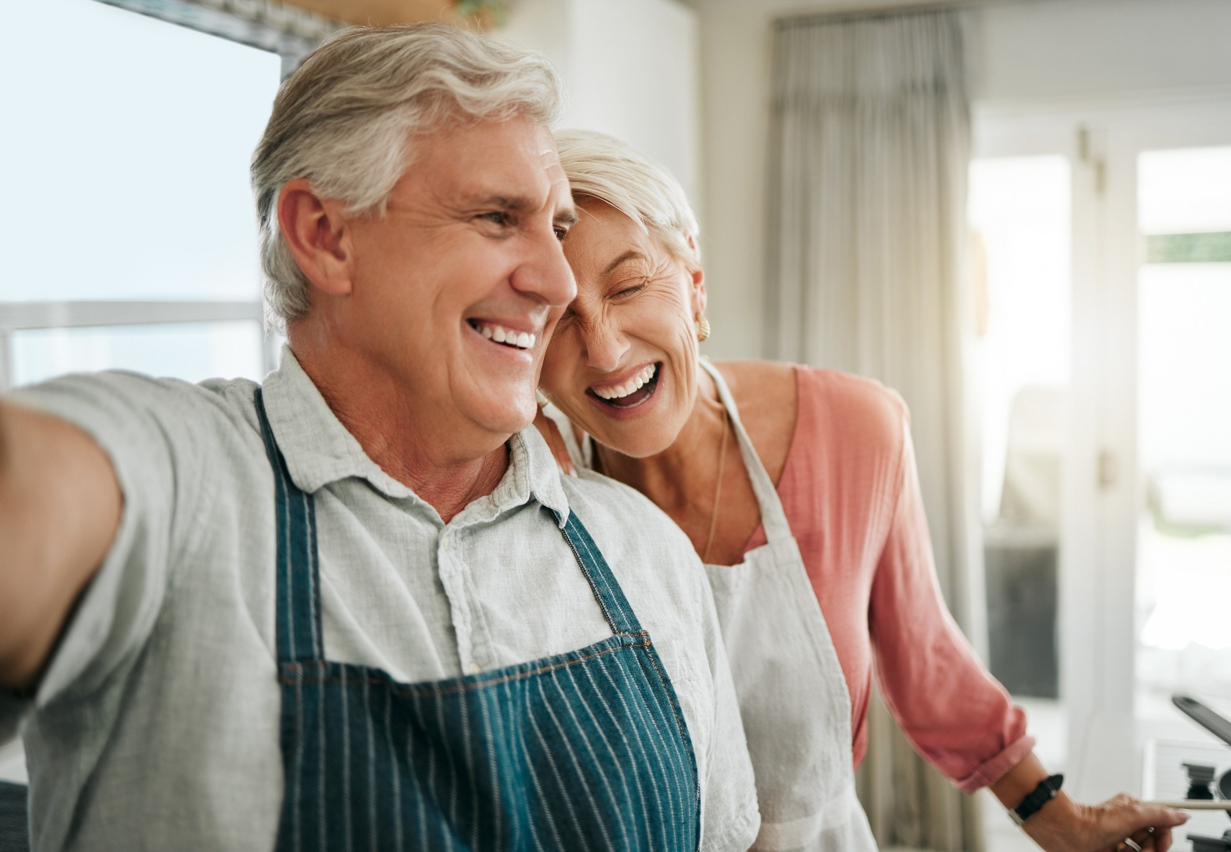 A senior couple laughing together in their kitchen