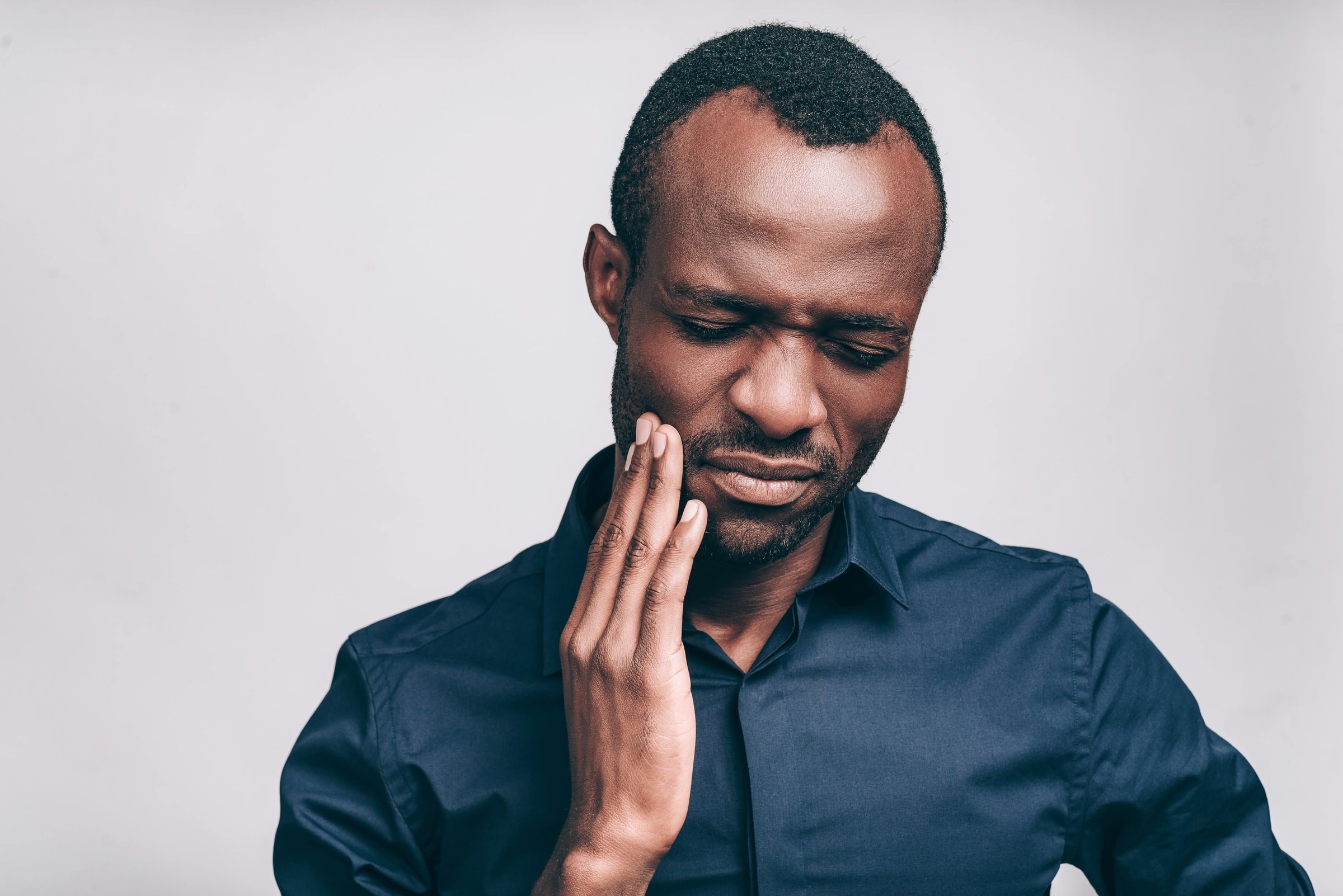 A man pressing his hand to his cheek because of tooth pain
