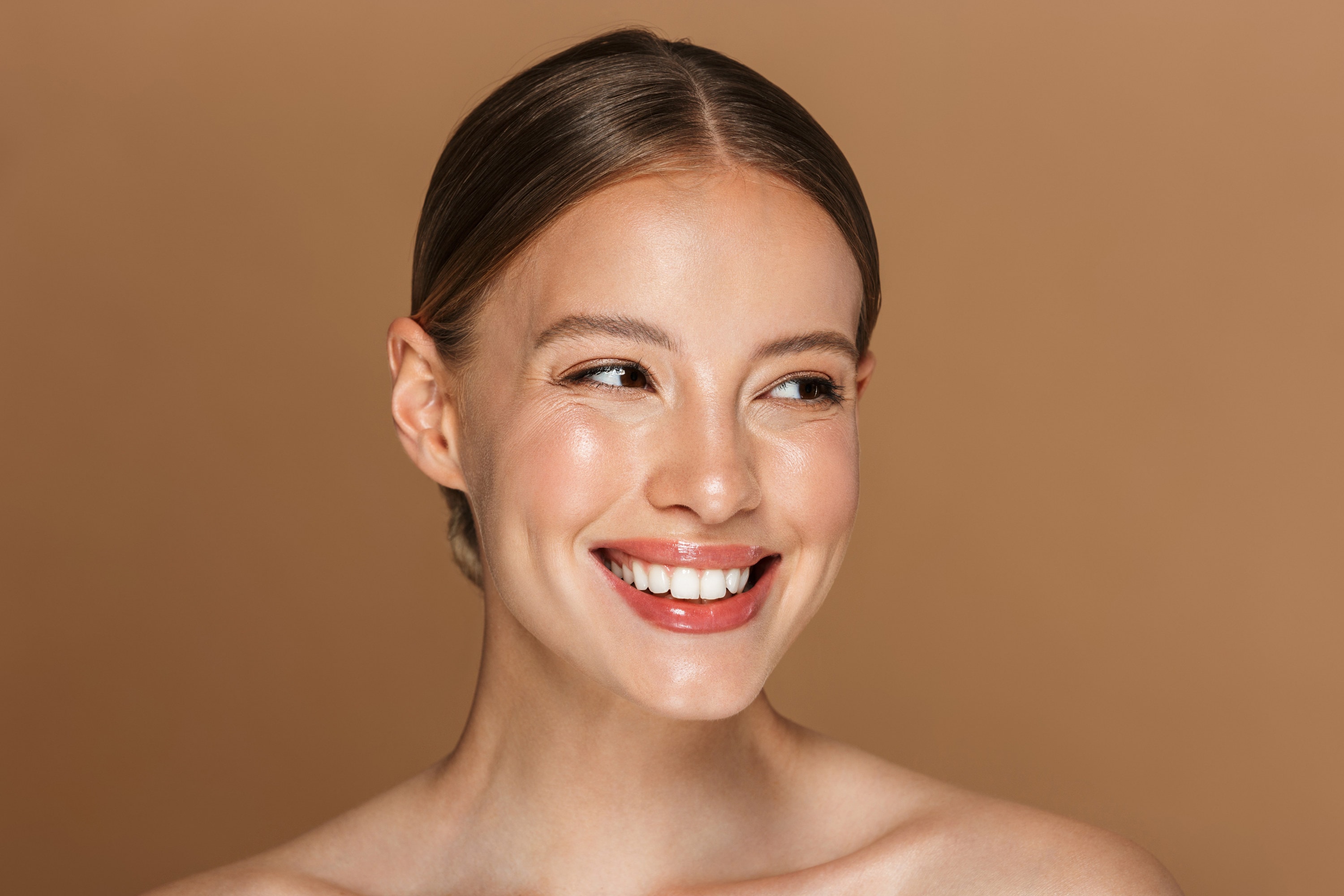 A young woman with a bright, natural smile against a warm brown background