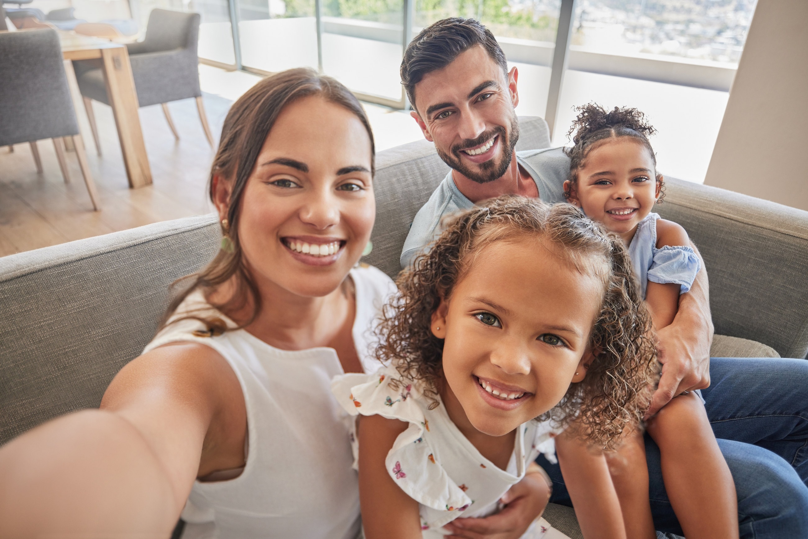 A smiling family taking a selfie together on the living-room sofa